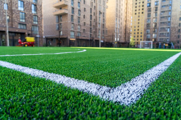 Outer line in soccer stage on green artificial turf in courtyard of residential building. Soccer...