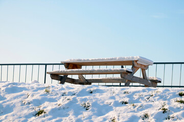 A snow-covered bench and a table in a winter park.