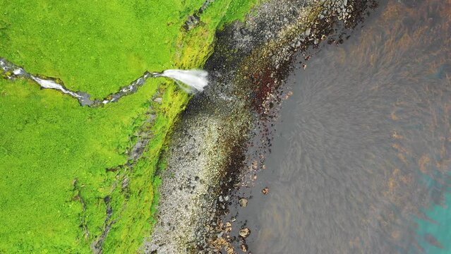Aerial view of a waterfall along the coast, Driftwood Bay, Unalaska island, Alaska, United States.