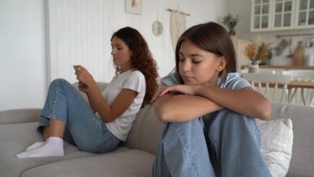 Miffed angry woman mom together resentful girl child quarrelled turned away from each other ignore talking after family fight. Unhappy mother with sad teen daughter avoid speaking sit separate at home
