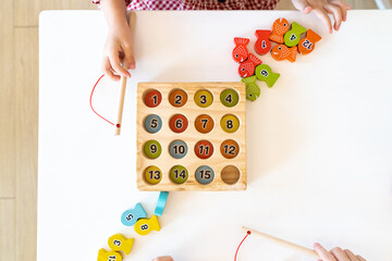 Topview, flatlay of Kid's hands are playing and finding the matched number in the wooden magnetic...