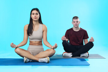 Young meditation couple; teenage man and woman sitting on mats in asana poses