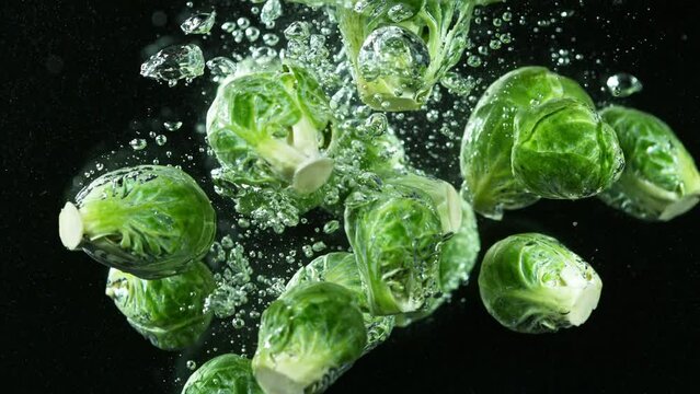 Super slow motion of falling cabbage pieces into water. Isolated on black background. Filmed on high speed cinema camera, 1000fps. Speed ramp effect.