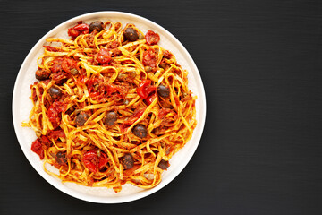 Homemade Tuna Linguine Pasta with Tomatoes, Olives and Capers on a Plate on a black background, top view. Overhead, from above, flat lay. Copy space.