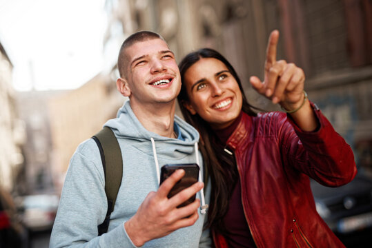 Young teenage couple visiting a foreign city, looking at the landmarks around them, navigating with their phone