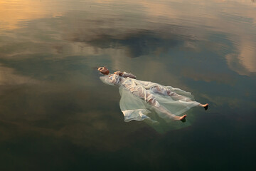 Floating dead bride in sunset colored waters