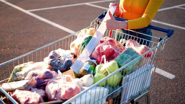 A woman's hand pointing thump up, after shopping, the basket full of food,