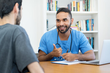 Positive young hispanic doctor or nurse talking with patient