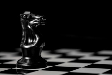 Close up of Chess pieces on a reflective mirror board surface with black background