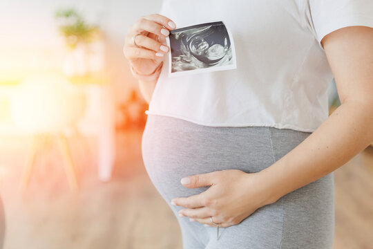 Concept banner expectant mother waiting for baby birth during pregnancy, light home background. Pregnant woman with ultrasound image with sunlight
