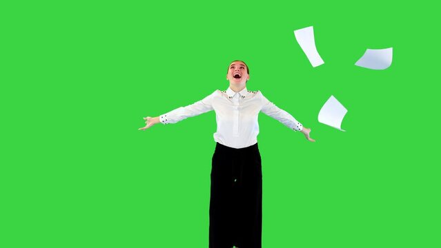 Positive caucasian girl throws away office papers and start dancing happily on a Green Screen, Chroma Key.