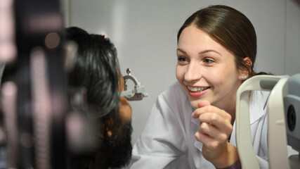 Attentive female optometrist examining eyesight of patient with special medical device. Eye health check and ophthalmology concept