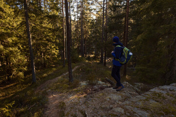 A man with a backpack standing in a forest at sunrise.