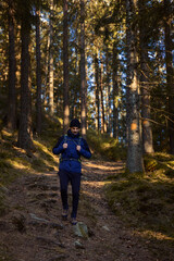 Obraz premium A caucasian man with a backpack hiking in the forest on a path with sun shinning.