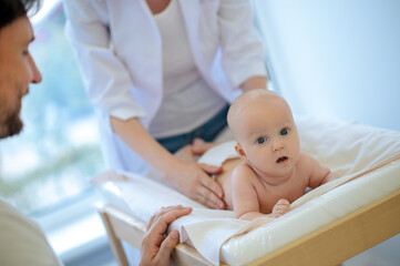 Cute baby being examined by pediatrician and looking surprised