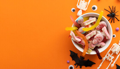 A bowl full of halloween candy sweets on an orange background. Trick or treat background