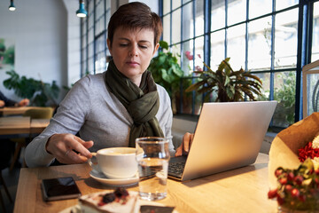 Woman working on a notebook and drinking coffee in a cafe