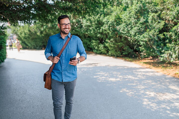 Excited young entrepreneur or businessman, walking down the street, using mobile.