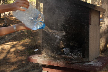 A man hand extinguished the fire in a grill with a bottle of water. Long exposure