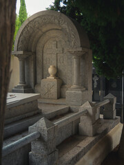 vertical photo of a tomb in a Christian cemetery adorned with a carved floral design with an urn...