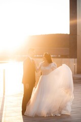 Fototapeta na wymiar The newlyweds pose at sunset near the lake