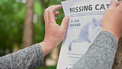 man sticking flyers and seeking for a missing cat in a park