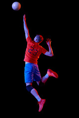 Male professional volleyball player in sports uniform training with ball isolated on dark background. Sport, power, action, healthy lifestyle, team sport