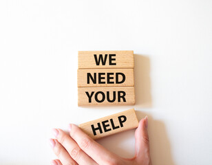 We need your help symbol. Wooden blocks with words We need your help. Beautiful white background. Businessman hand. Business and We need your help concept. Copy space.