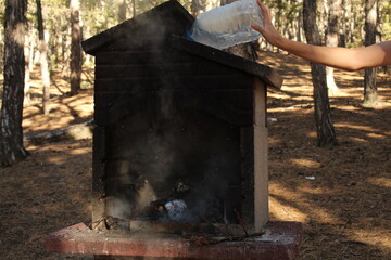 A man hand extinguished the fire in a grill with a bottle of water. Long exposure