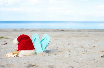 Santa Claus hat and beach sleepers on the beach 