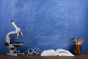 Back to school - books and microscope on the desk, Education concept. Blackboard background