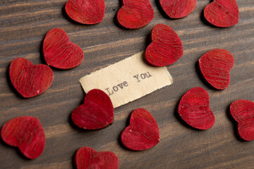 Love you - typed text. Valentines Day greetings concept. Little red wooden hearts close up....