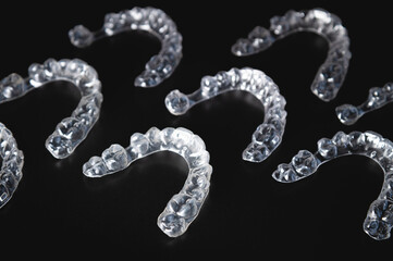 a pattern of invisible plastic aligners lie on a black background