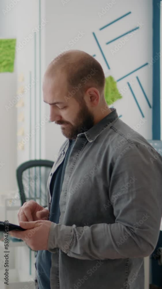 Poster vertical video: man engineer designing architectural plan on tablet with building model and maquette