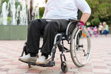 Obraz premium Unrecognizable woman with disability sitting in wheelchair in the street close up