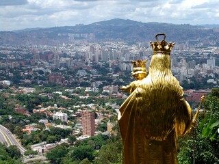 Naklejka premium Golden statue of Virgen Maria Auxiliadora with the city background