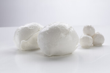 Whole mozzarella with morsels of fresh mozzarella on a white background