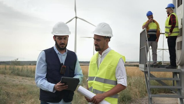 Professional team of engineer and electrical technicians working in wind turbine electricity farm, planing renewable green energy project