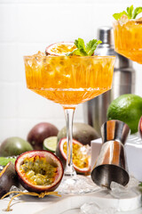 Passion fruit martini cocktail. Sweet pornstar alcoholic drink with fresh passion fruit and lime, with bar utensils copy space