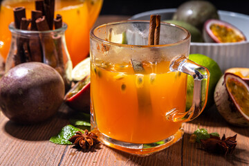 Passion fruit hot tea drink with fruity juice, cinnamon, lime, over wooden background with fresh...
