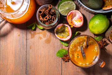 Passion fruit hot tea drink with fruity juice, cinnamon, lime, over wooden background with fresh passion fruit and spices
