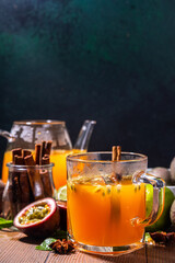 Passion fruit hot tea drink with fruity juice, cinnamon, lime, over wooden background with fresh passion fruit and spices
