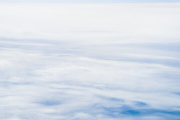 Fototapeta premium Flying Above the Clouds with Blue Skies in an Airplane Looking out of the Window. White fluffy clouds below with the darkness of space. Beautiful white clouds.