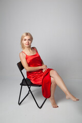 Fototapeta premium girl in a red dress sitting on a chair