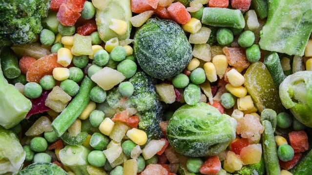 4k zoom in out Different frozen vegetables as background, top view. Stocking up vegetables for winter storage. Assortment of frozen vegetables. Healthy food, Cooking ingredients