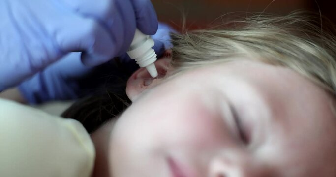 Child with otitis media is given antibiotic drops in ear closeup 4k movie slow motion
