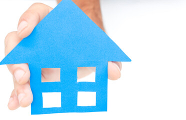 
close up hand holding a blue paper house on white background. Concept of housing, buying and selling houses, rentals, real estate, mortgage