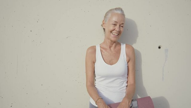 Cinematic footage of a beautiful senior fashion influencer with silver hair and fashionable style. Elderly active woman doing activities outdoor in a modern part of the city