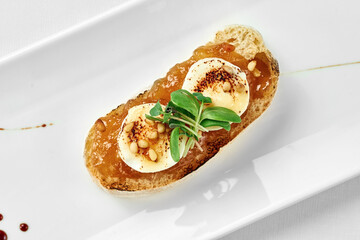 Bruschetta with pear and goat cheese on a white plate against a white background. Close-up, selective focus