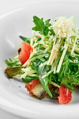 Salad with eel and grapefruit on a white plate against a white background. Close-up, selective focus